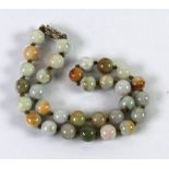 SINGLE STRAND NECKLACE OF 31 UNIFORMLY SIZED BUT VARIED COLOUR JADE BEADS with paste sterling clasp