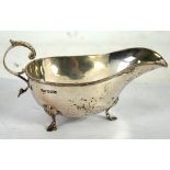 A SILVER PLAIN OVAL SAUCE BOAT with reel and ribbon border, acanthus free scroll handle, raised on