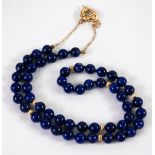 SINGLE STRAND NECKLACE OF UNIFORM LAPIS LAZULI BEADS with seven 9ct gold beads and ring clasp and