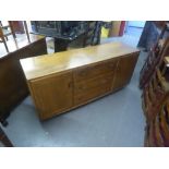 ERCOL LIGHT ELM SIDEBOARD WITH CENTRAL NEST OF THREE DRAWERS, FLANKED BY CUPBOARDS ALL WITH RECESSED