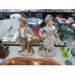 *A PAIR OF TINTED BISQUE FIGURES, STREET VENDORS, 14" HIGH