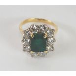 A YELLOW AND WHITE GOLD EMERALD AND DIAMOND SET RING, the central claw set rectangular emerald