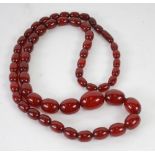 NECKLACE OF DARK RED AMBER GRADUATED OVAL BEADS, 55 beads, approx 87gms