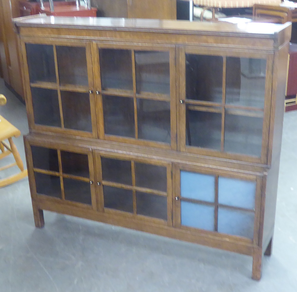 AN EDWARDIAN OAK GLAZED BOOKCASE/SIDE CABINET, THE UPPER TIER OF THREE GLAZED DOORS, THE LOWER