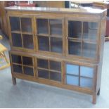 AN EDWARDIAN OAK GLAZED BOOKCASE/SIDE CABINET, THE UPPER TIER OF THREE GLAZED DOORS, THE LOWER