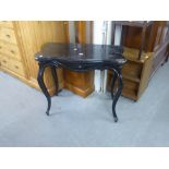 AN EBONISED FOLD-OVER CARD TABLE WITH OUT-SWEPT LEGS (A.F.)