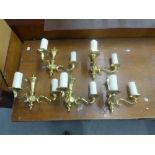 A SET OF FIVE BRASS TWO LIGHT WALL BRACKETS WITH CANDLE PATTERN SCONCES AND FABRIC SHADES