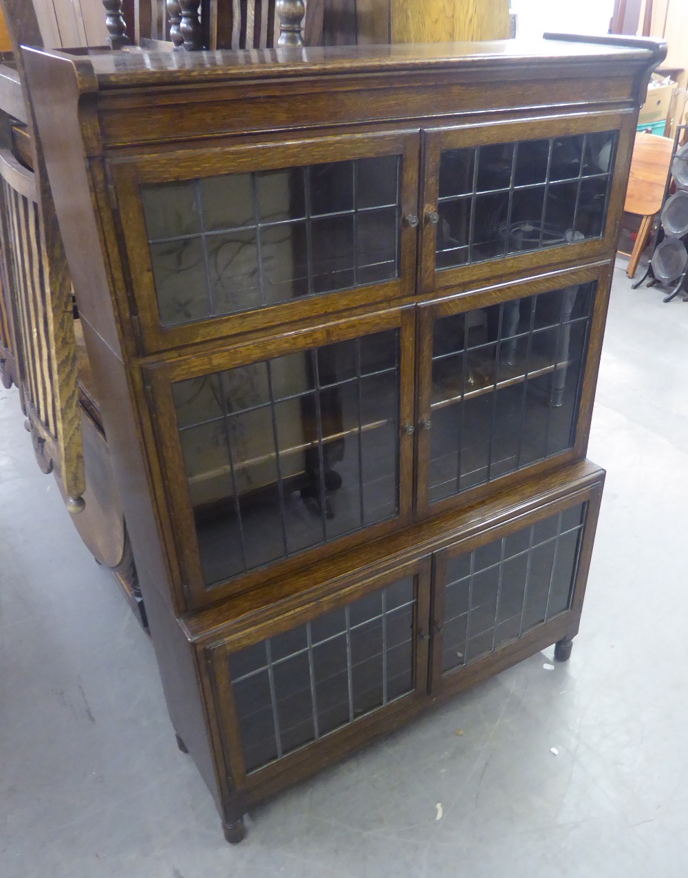 AN EARLY TWENTIETH CENTURY 'MINTY' OAK THREE SECTION BOOKCASE WITH LEADED DOORS