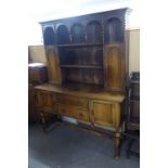 AN EARLY TWENTIETH CENTURY OAK DRESSER, the top section having open plate rack flanked by two