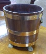A MODERN OAK AND BRASS BOUND BUCKET SHAPED RECEIVER with brass lion mask and ring handles and paw