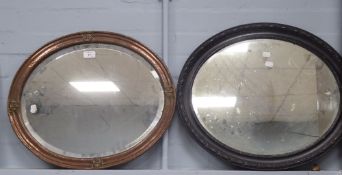AN OVAL BEVELLED EDGE WALL MIRROR, in beaten copper cavetto frame, decorated with four heraldic