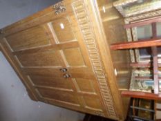 A GOOD QUALITY JACOBEAN STYLE CARVED OAK MILLINERY CABINET WITH TWO FRAMED FOUR PANEL DOORS