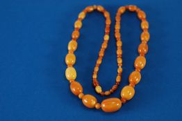 1920's SINGLE STRAND NECKLACE OF GRADUATED OVAL 'BUTTERSCOTCH' COLOURED AMBER BEAD with small