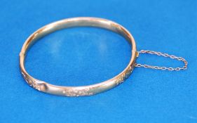 9ct GOLD HINGE OPENING HOLLOW BANGLE, the top engraved with foliate scrolls, Birmingham 1911, 7 gms