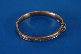 EDWARDIAN 9ct GOLD HINGE OPENING HOLLOW BANGLE, with foliate scroll engraved top, Birmingham 1902,