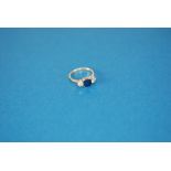 18ct GOLD AND PLATINUM RING, set with a centre square cut sapphire, 5mm wide, and two side round