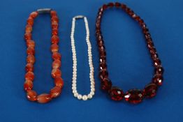 A GRADUATED FACET CUT BEAD NECKLACE of scarlet translucency, TOGETHER with a Cornelian bead NECKLACE