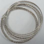 NINE NARROW SLAVE BANGLES, with facet decoration, marked 'Sterling'