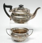 AN EARLY TWENTIETH CENTURY SILVER DEMI GADROONED ROUNDED OBLONG TEA POT, with blackwood handle and