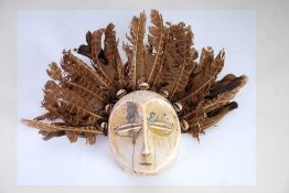 LEGA CARVED IVORY LUKUNGU MASK, with surround of cowrie shells and brown feathers, the mask, 4 ½"