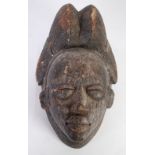 PUNU CARVED WOOD MAIDEN SPIRT MASK, Gabon, with high, ribbed, coiffure and diamond scarification