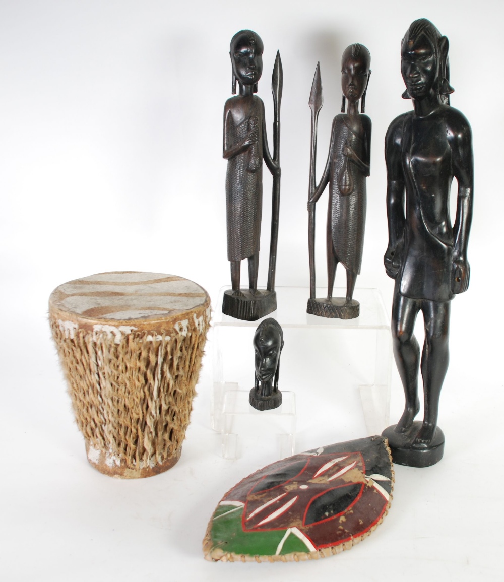 AFRICAN CARVED DARK WOOD FIGURE OF A WARRIOR, modelled standing holding an elliptical, painted