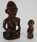 YOMBE CARVED WOOD MATERNITY FIGURE, modelled seated with a baby and bottle, on an oval base, 9" (