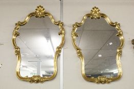 A PAIR OF GILT FRAMED WALL MIRRORS WITH SHAPED GLASS