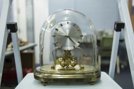 A KERN BRASS ANNIVERSARY CLOCK BENEATH GLASS DOME, WITH PRESENTATION PLAQUE DATED 1964
