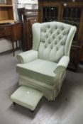 A MODERN FIRESIDE ARMCHAIR, GREEN VELVET UPHOLSTERY WITH BUTTON BACK AND THE FOOTSTOOL