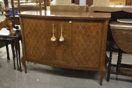 A REPRODUCTION LIGHT WOOD BOW FRONT SIDEBOARD, THE TWO DOOR FRONT WITH DECORATIVE MARQUETRY, ON