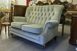 A TWO SEATER SETTEE IN GREEN VELVET