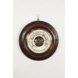 EARLY TWENTIETH CENTURY ANEROID BAROMETER in turned mahogany stained carved fruitwood surround, 13