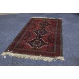 EASTERN RUG, with triple pole medallion, crimson and black colours with white highlights, zig-zag