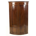 GEORGE III INLAID MAHOGANY BOW FRONTED CORNER CUPBOARD, the moulded cornice above a frieze inlaid