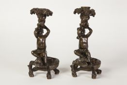 PAIR OF BRONZE FIGURAL CANDLE HOLDERS, each cast as nude cherubs sat on the back of a crocodile, 8