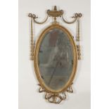 EDWARDIAN GILT WOOD AND GESSO WALL MIRROR, in the neo classical style, the oval, bevel edged plate