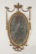 EDWARDIAN GILT WOOD AND GESSO WALL MIRROR, in the neo classical style, the oval, bevel edged plate