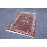 EASTERN RUG wit midnight blue petal shaped centre medallion and spandrels on a crimson field with