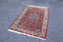 EASTERN RUG wit midnight blue petal shaped centre medallion and spandrels on a crimson field with