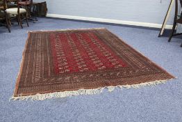 PAKISTAN BOKHARA CARPET WITH FOUR ROWS OF GULS on a crimson field, the broad borders having multiple