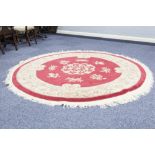 CIRCULAR WASHED CHINESE CARPET with embossed design on a crimson field, floral centre medallion