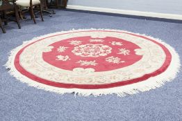 CIRCULAR WASHED CHINESE CARPET with embossed design on a crimson field, floral centre medallion