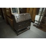 A TWENTIETH CENTURY OAK BUREAU FALL-FRONT WITH FITTED COMPARTMENTS OVER TWO SHORT AND ONE LONG