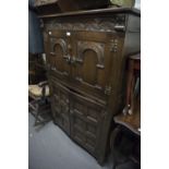 JACOBEAN STYLE CARVED OAK FOUR DOOR COCKTAIL CABINET WITH PULL-OUT GLASS INSET SLIDE AND COCK'S HEAD