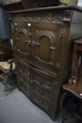 JACOBEAN STYLE CARVED OAK FOUR DOOR COCKTAIL CABINET WITH PULL-OUT GLASS INSET SLIDE AND COCK'S HEAD