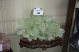 A CARVED GREEN JADE FLORAL ORNAMENT AND WOODEN STAND (A.F.)