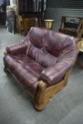 A RED LEATHER TWO SEATER SETTEE WITH DRAWERS BELOW FOR STORAGE