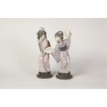 TWO LLADRO PORCELAIN ORIENTAL FEMALE FIGURES, each modelled standing wearing a kimono and holding