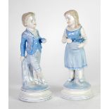 PAIR OF VICTORIAN PORCELAIN FIGURES OF A YOUNG BOY AND GIRL both modelled carrying or holding fruit,